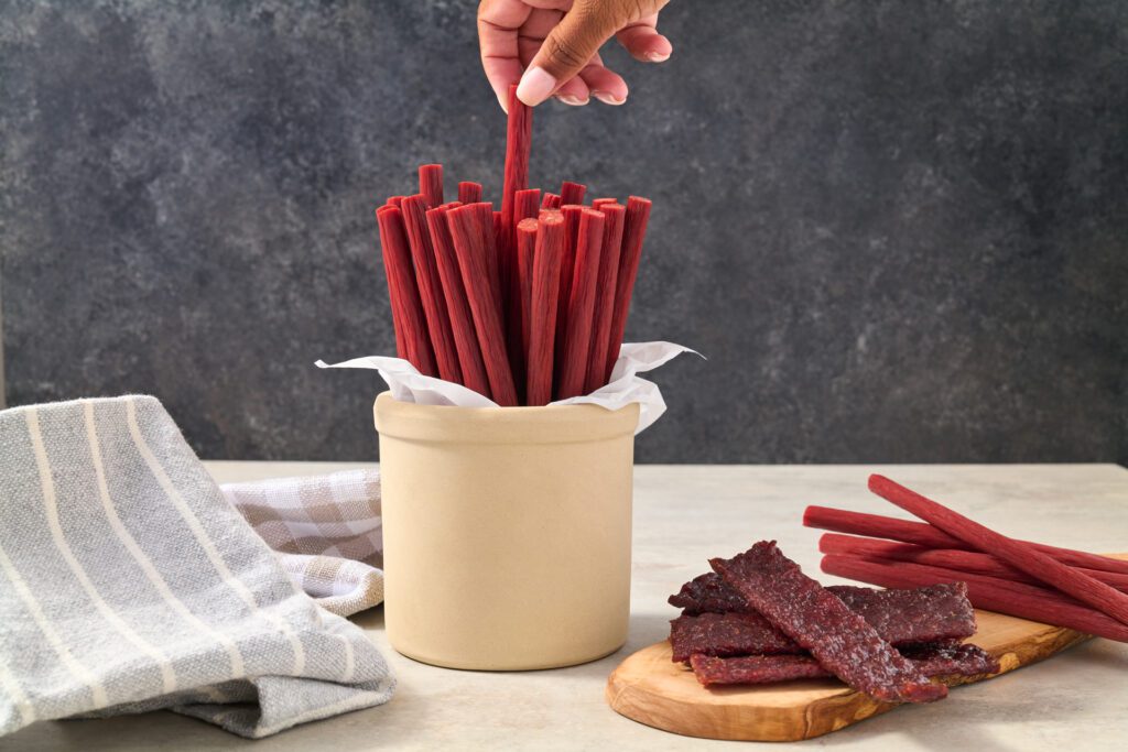 Image of hand grabbing snack stick, used as featured image on blog about carnivore diet